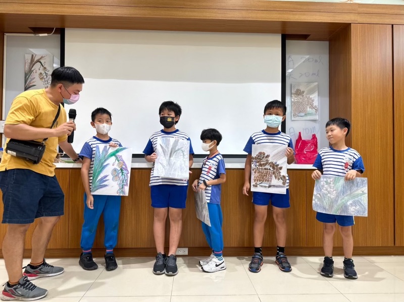學生舉起完成的作品,與導覽老師合影